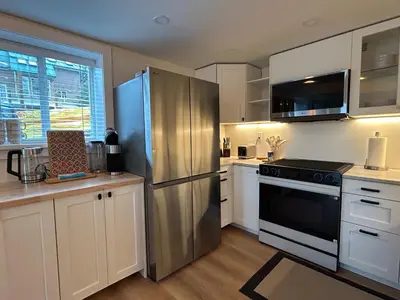 a kitchen with a stainless steel refrigerator and white cabinets at 2BR Seaside Haven Retreat