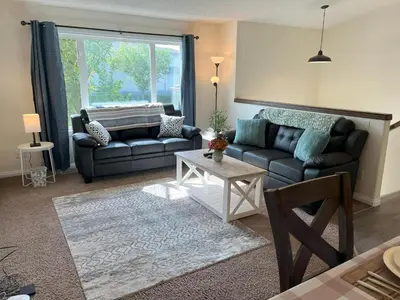 a living room with a couch and a table at 3 Adjacent 4-bed Homes - Park Views, Fully Stocked in Grande Prairie