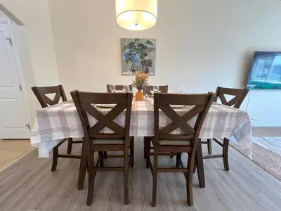 a dining room table with chairs and a tablecloth on it at 3 Adjacent 4-bed Homes - Park Views, Fully Stocked in Grande Prairie
