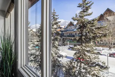 a window with a christmas tree in the snow at Mountain Escape 2BR Hot tub and Pool Near Banff in Canmore