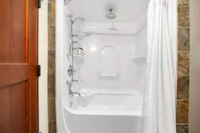 a white bath tub with a shower curtain in a bathroom at Mountain Escape 2BR Hot tub and Pool Near Banff in Canmore