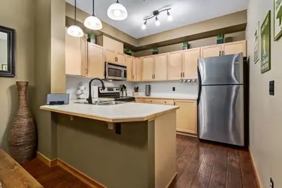 a kitchen with a stainless steel refrigerator and wooden cabinets at Spacious Getaway near Banff with Heated Pool in Canmore