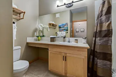 a bathroom with a sink and a toilet and a mirror at Spacious Getaway near Banff with Heated Pool in Canmore
