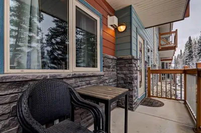 a porch with a wooden table and a chair at Spacious Getaway near Banff with Heated Pool in Canmore