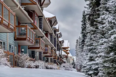 a building in the snow with snow covered trees at Spacious Getaway near Banff with Heated Pool in Canmore