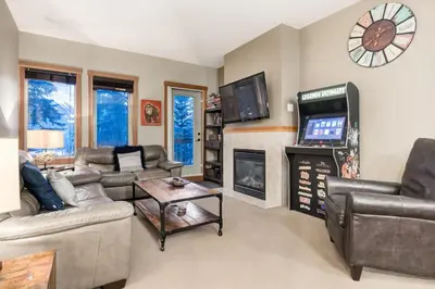 a living room with couches and a tv and a fireplace at Spacious Getaway near Banff with Heated Pool in Canmore