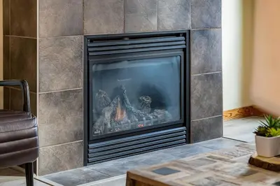 a fireplace in a living room with a tile wall at 3BR Rockies Condo Heated Pool and Hot Tub in Canmore