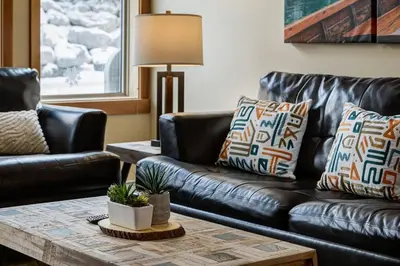a living room with a leather couch and a coffee table at 3BR Rockies Condo Heated Pool and Hot Tub in Canmore
