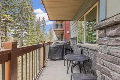 a balcony with a table and chairs on a house at Chic 1BR City Nest Heated Parking and Hot Tub and Pool in Canmore