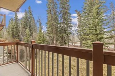 a balcony with a view of the woods at Chic 1BR City Nest Heated Parking and Hot Tub and Pool in Canmore