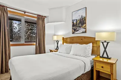 a bedroom with a bed and two lamps and a window at 3BR Family Friendly Getaway Pool and Hot Tub in Canmore