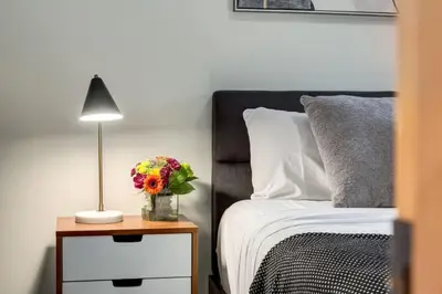 a bedroom with a bed and a table with a vase of flowers at Lovely 2BR Canmore Condo w Heated Pool and Hot Tub in Canmore