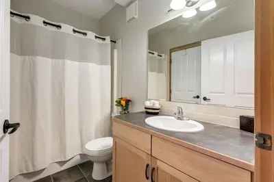a bathroom with a sink and a toilet and a mirror at Lovely 2BR Canmore Condo w Heated Pool and Hot Tub in Canmore