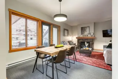 a dining room with a table and chairs and a living room at Lovely 2BR Canmore Condo w Heated Pool and Hot Tub in Canmore
