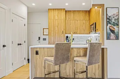 a kitchen with wooden cabinets and two bar stools at Spacious 2BR Minutes from Downtown w Pool and Hot Tub in Canmore