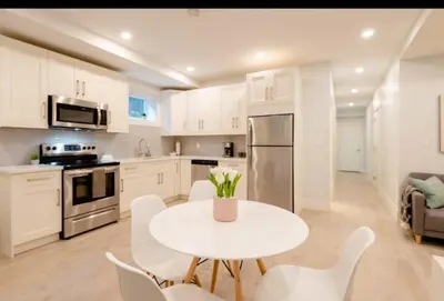 a white kitchen with a white table and chairs at 2BR Suite Close to Transit - Great for FIFA Vancouver in Burnaby