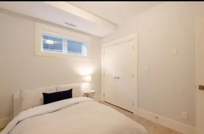 a white bedroom with a bed and a window at 2BR Suite Close to Transit - Great for FIFA Vancouver in Burnaby