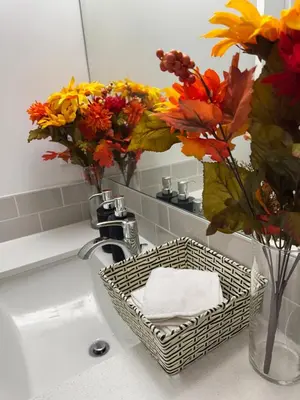 a bathroom sink with a basket of towels and flowers at Luxury Haven by Kc & Flo in Calgary