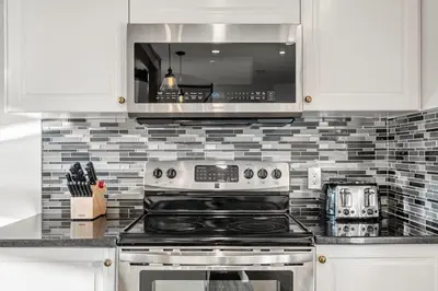 a kitchen with a stove and a microwave at Bright & Spacious 5-BR & Ravine Views in Edgemont in Calgary