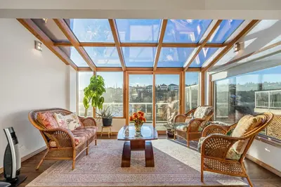 a conservatory with chairs and a table in a room with windows at Bright & Spacious 5-BR & Ravine Views in Edgemont in Calgary