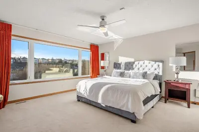 a bedroom with a bed and a large window at Bright & Spacious 5-BR & Ravine Views in Edgemont in Calgary