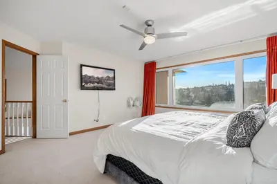 a bedroom with a bed and a large window at Bright & Spacious 5-BR & Ravine Views in Edgemont in Calgary