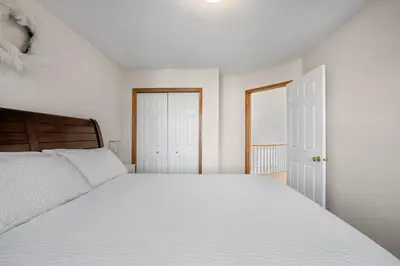 a bedroom with a white bed and a white door at Bright & Spacious 5-BR & Ravine Views in Edgemont in Calgary