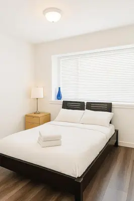 a white bedroom with a large bed with a window at Sweet 2-bedrooms house in Vancouver in Vancouver