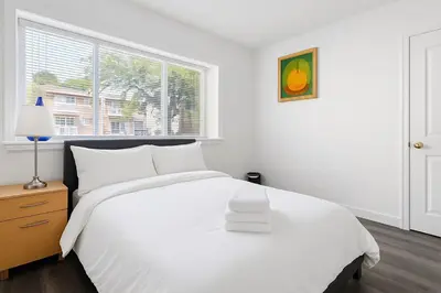 a white bedroom with a white bed and a window at Sweet 2-bedrooms house in Vancouver in Vancouver