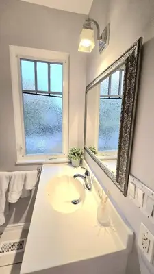 a white bathroom with a sink and a mirror at Spacious & Cozy House Near Lonsdale, Peaceful North Vancouver Stay in North Vancouver