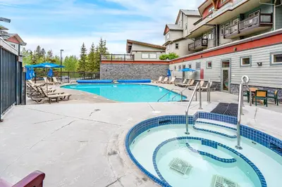 a swimming pool at a resort with tables and chairs at Sleeps 8 Loft with Pool Hot Tub Near Banff in Canmore