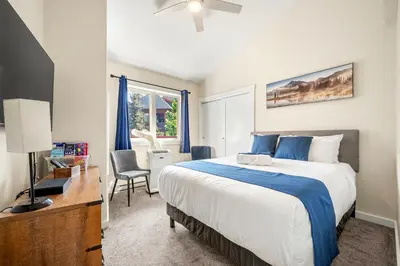 a bedroom with a bed and a desk and a window at Sleeps 8 Loft with Pool Hot Tub Near Banff in Canmore