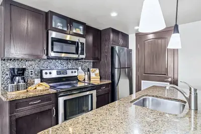 a kitchen with wooden cabinets and a stainless steel refrigerator at Rockies Getaway 2BR with Patio Hot Tub and Gym in Dead Man's Flats
