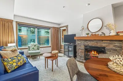 a living room with a blue couch and a fireplace at Contemporary 2BR with hot tub and Mountain Views in Dead Man's Flats