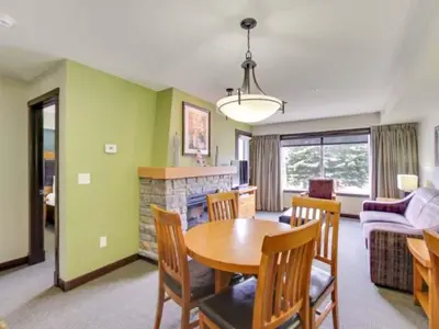 a living room with a table and a fireplace at Cozy Condo With Hot Tub Gym and Underground Parking in Dead Man's Flats