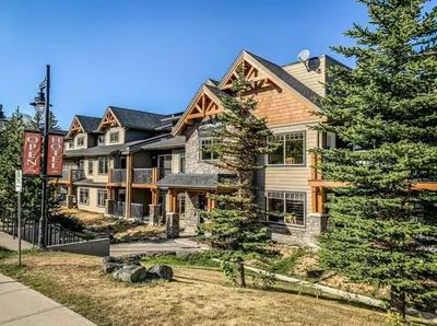 a large house with trees in front of it at Amazing 3BR Condo With Hot Tub Access and Mtn Views in Dead Man's Flats