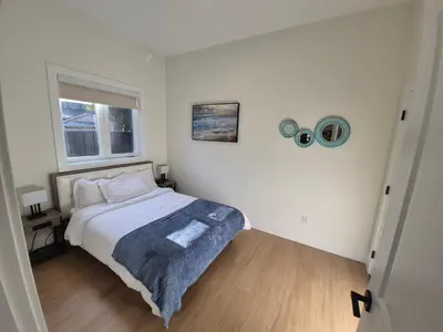 a small bedroom with a bed and a window at Sunny Skies Suites in Surrey