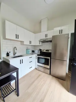a kitchen with white cabinets and a stainless steel refrigerator at Sunny Skies Suites in Surrey