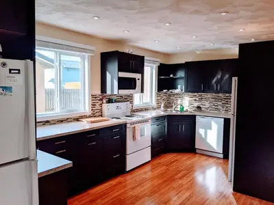 a kitchen with black cabinets and white appliances at Dragon's End Guesthouse in Massett