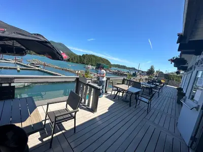 a man standing on a deck with tables and chairs at Island West Resort-Motel in Ucluelet