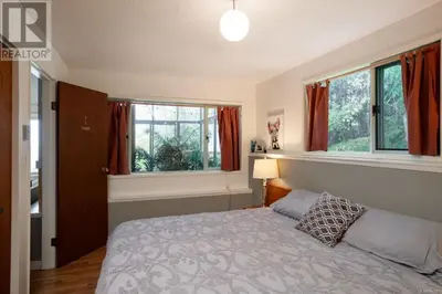 a bedroom with a bed and two windows at The Mushroom Manor B&B and Cedar Sauna in Salt Spring Island