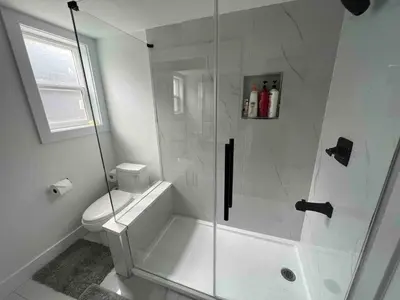 a white bathroom with a shower and a toilet at Ricky's Apartment in Delta