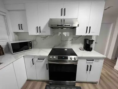 a kitchen with white cabinets and a stove top oven at Ricky's Apartment in Delta