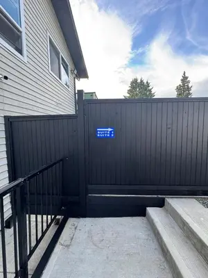 a black fence next to a house with a gate at Brand new fully Private Garden suite 2 in Delta