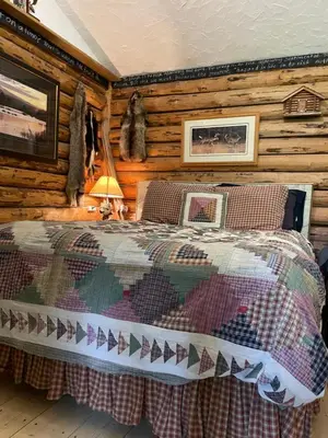 a bedroom with a bed in a log cabin at Cozy Country Log Cabin Art Spa Getaway in Caroline