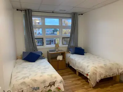 two beds in a room with a window at ArtHaus Downtown Emma Barr Unit 3BR 1BA in Whitehorse
