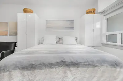 a white bedroom with a large bed and a window at Vita Resort Vernon - Modern Studio on Okanagan Lake in Vernon