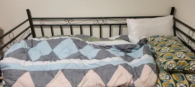 a bed with a quilt and a dog laying on it at Single Court in Abbotsford