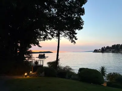 a view of a lake with a tree and the sunset at Oceanside Getaway in Nanoose Bay