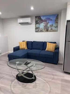 a living room with a blue couch and a glass table at The Lakefront - A new 2-bedroom in Mahogany Calgary in Calgary
